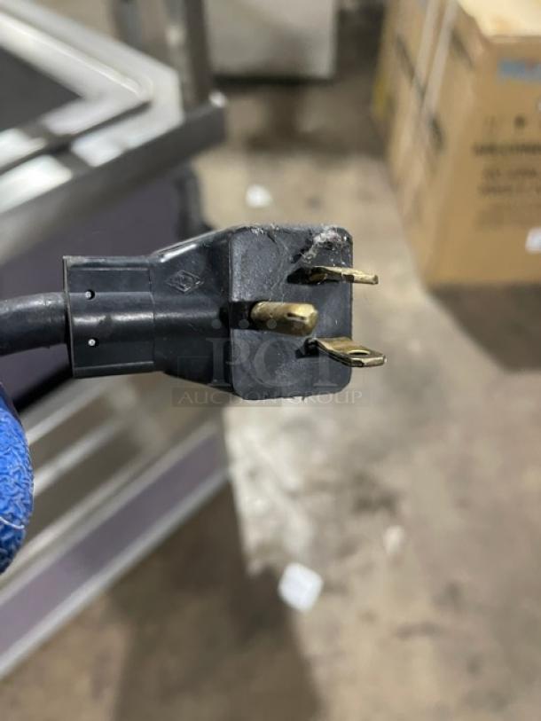 Close-up of plug for Atlas Metal WCMBT4 refrigerated salad bar. Features three prongs, visible wear, and black casing.