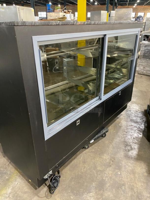 Commercial black bakery display case with curved glass, multi-tier shelves, lower overstock compartment, and rear sliding doors.
