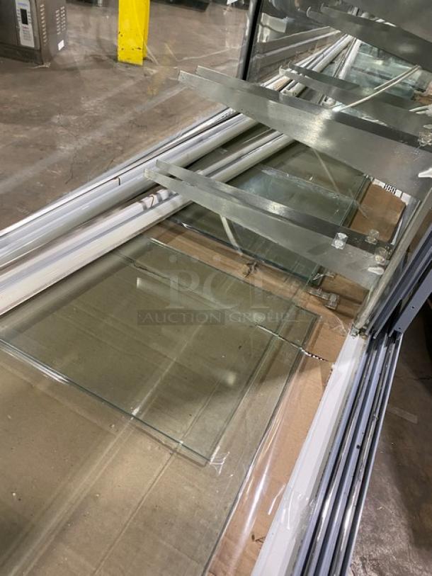 Commercial black curved glass multi-tier bakery display case with lower compartment and rear sliding doors. Visible shelves.