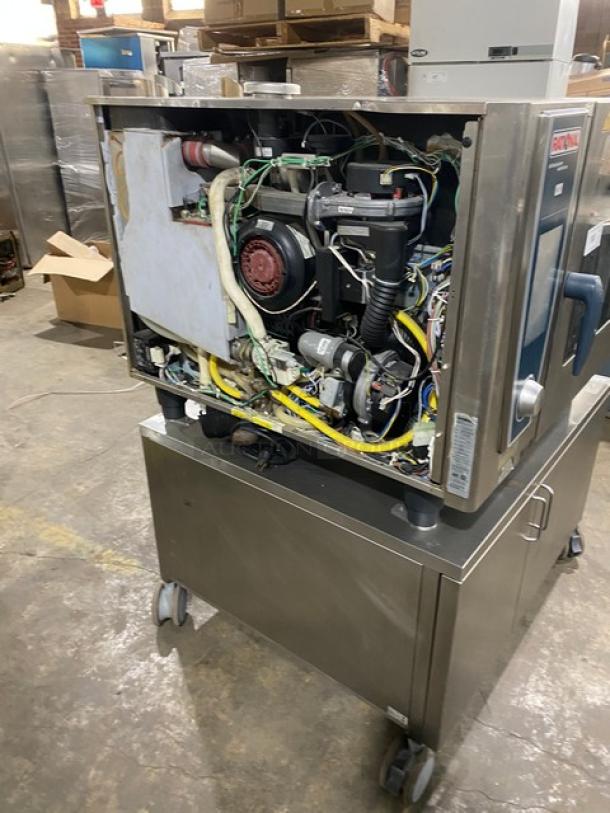 Rational SCCWE62G commercial stainless steel combi oven, open side panel showing internal parts, on equipment stand with casters.