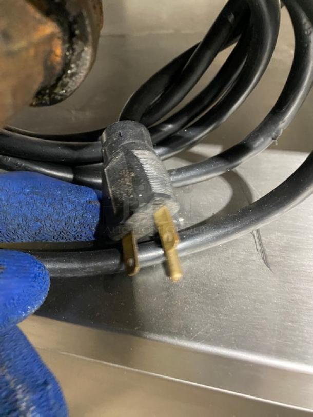 Close-up of the power cord for a Rational SCCWE62G combi oven, showing prongs and protective blue glove.