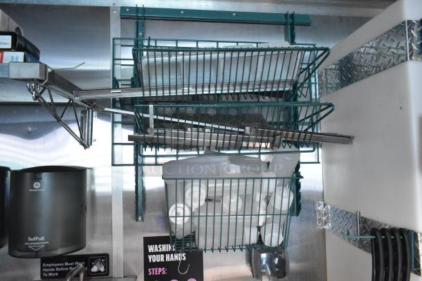 Interior of a Cruising Kitchens food trailer showing metal racks holding white bottles and kitchen utensils.