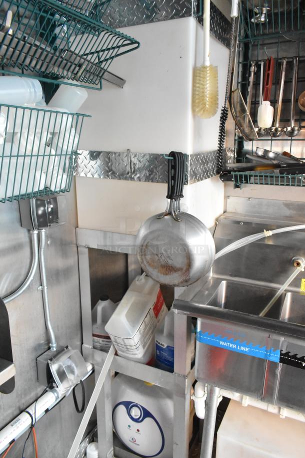 Cruising Kitchens 24' food trailer kitchen interior, featuring stainless steel sink, hanging cookware, and storage racks.