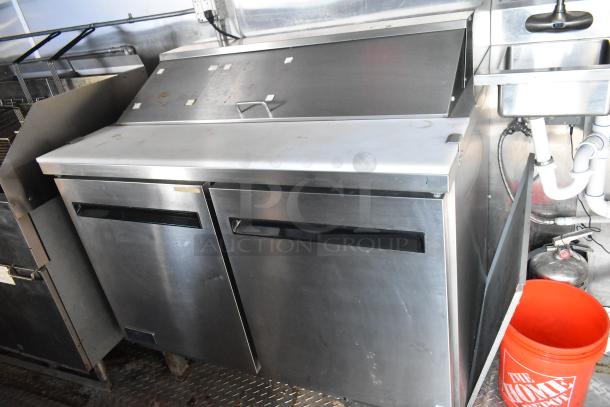 Stainless steel Arctic Air prep table in a fully equipped food trailer kitchen, featuring dual doors and a prep area.