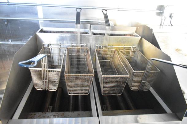 Commercial fryer baskets inside Cruising Kitchens 24' food trailer. Stainless steel finish, ideal for various culinary concepts.
