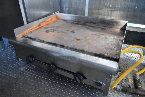 Wells griddle in Cruising Kitchens 24' food trailer, used condition, with dual control knobs, on steel flooring.