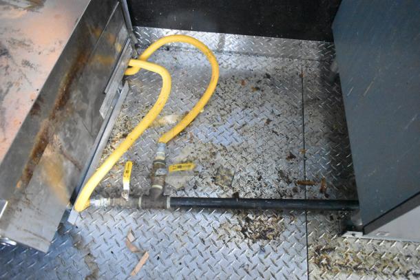 Diamond plate metal flooring inside Cruising Kitchens food trailer, showing yellow gas lines and metal piping setup.
