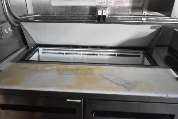 Commercial-grade prep table in Cruising Kitchens food trailer, featuring stainless steel construction and a lift-top design.