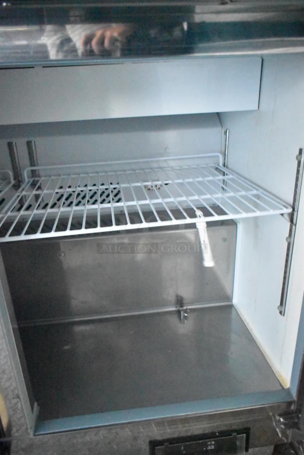 Interior view of a Cruising Kitchens food trailer's cooler; includes a wire shelf and metal interior, showcasing its spacious design.