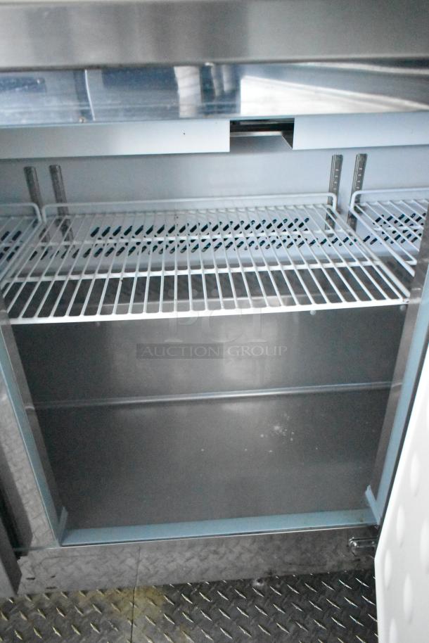 Interior view of a Cruising Kitchens food trailer, featuring stainless steel shelves and Arctic Air storage units. Brand new condition.