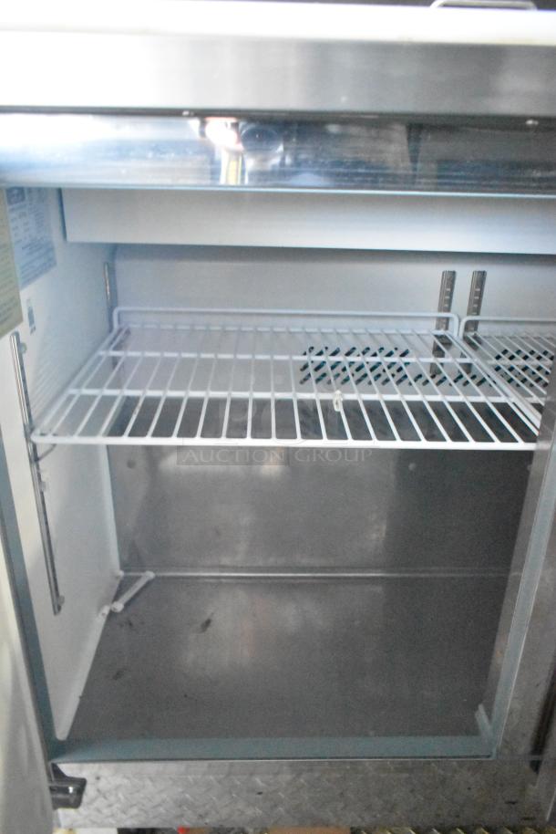 Interior view of an Arctic Air undercounter cooler/freezer in a new 24' Cruising Kitchens food trailer. Features wire rack shelving and stainless steel finish. Clear title included.