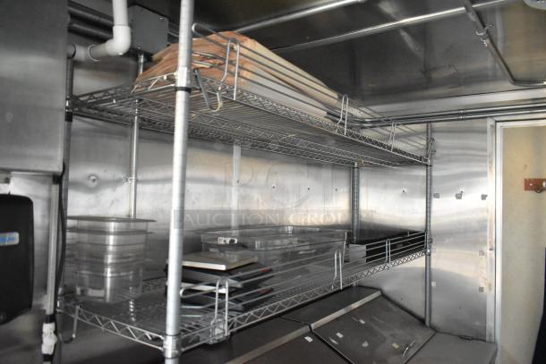 Inside view of a 24' Cruising Kitchens food trailer, featuring stainless steel shelving, prep tables, and undercounter coolers.