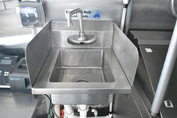 Stainless steel sink with hand wash sign, part of a 24' Cruising Kitchens food trailer. Equipped for commercial use.
