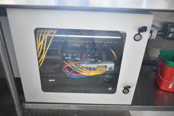 APC network cabinet in a Cruising Kitchens food trailer, showing organized yellow and red cables and secured with a key lock.