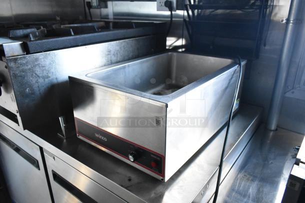 Fully-equipped interior of a 2021 Cruising Kitchens 24' food trailer, featuring a stainless steel Winco food warmer, commercial-grade cooktops, and undercounter storage.