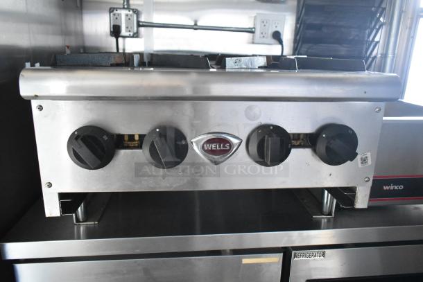 Wells griddle with four control knobs inside a Cruising Kitchens 24' food trailer, featuring commercial-grade equipment.