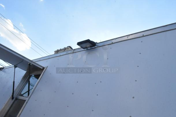 Exterior of a 2021 Cruising Kitchens 24' food trailer with vent and window. Ideal for mobile kitchen setup.