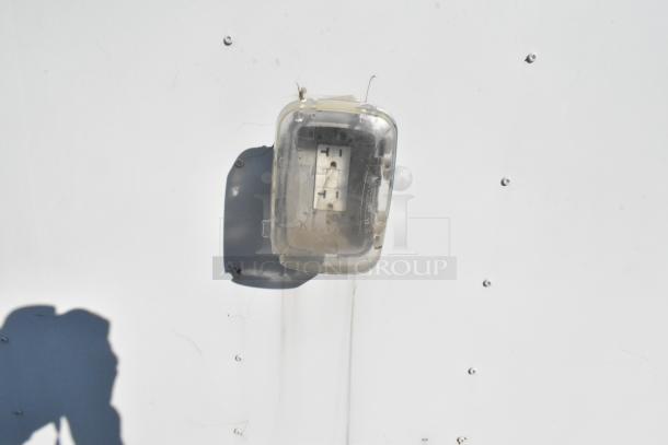Outdoor electrical outlet with protective cover on a white food trailer exterior. Cover is slightly translucent and secured.