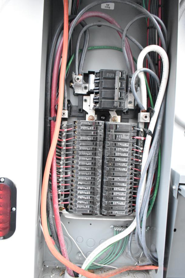 Electrical panel inside Cruising Kitchens food trailer, featuring circuit breakers and wiring.