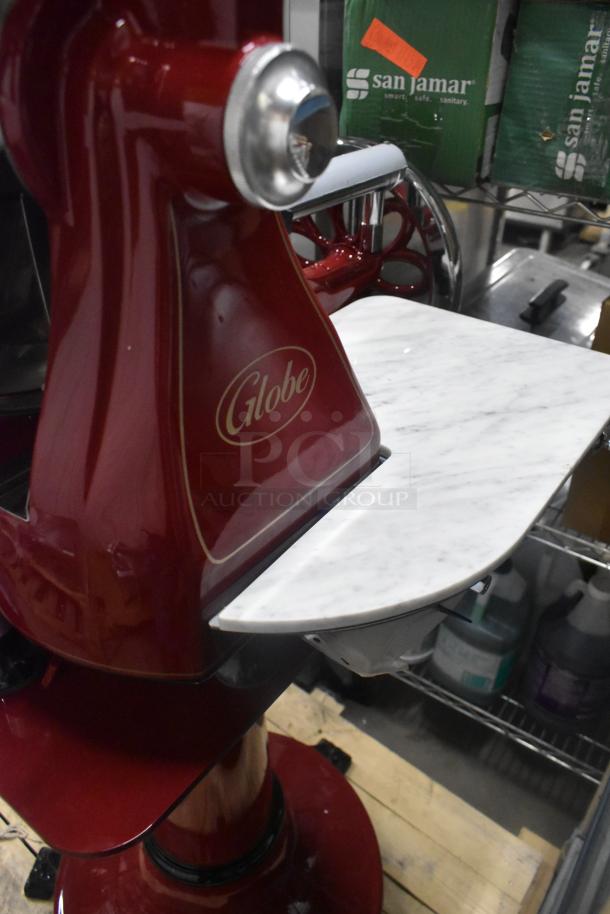 Brand new Globe metal commercial flywheel meat slicer with blade, featuring a red finish and marble-style platform.