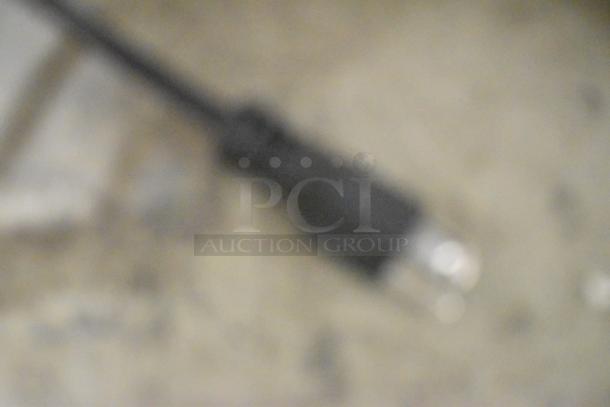 Blurry image of an electrical plug on a surface. No visible details or markings.