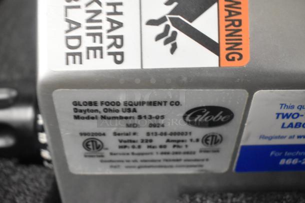 Close-up of Globe S13-05 label showing model number, voltage, and warnings. Brand new stainless steel countertop meat slicer.