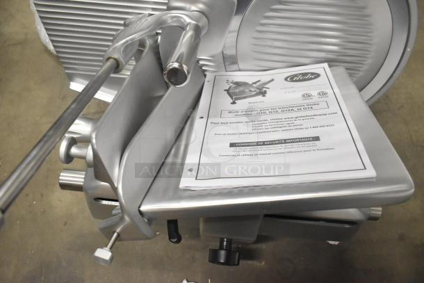 Brand new Globe stainless steel manual meat slicer with blade sharpener, 110 volts, 1 phase. Instruction manual visible.