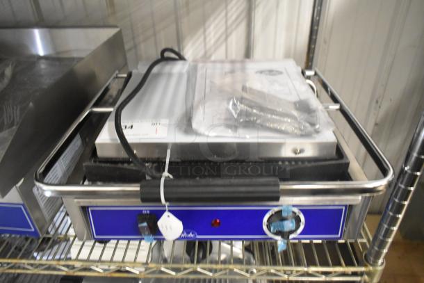 Brand new Globe GPG1410 stainless steel commercial panini press, 120 volts, 1 phase, with control dials and protective casing.