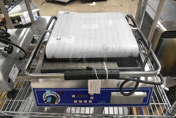Brand new Globe GPG14D stainless steel commercial panini press on a countertop. Features temperature dial and digital display. 120V, 1 Phase. Tags indicate model and voltage.