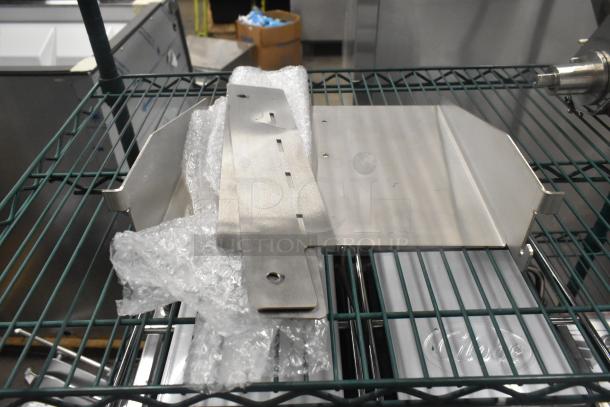 Brand new metal pieces on a wire shelf, partially wrapped in bubble wrap. Appears sturdy and clean for industrial use.