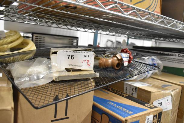 Lot of various items including metal handles and a mesh rack, labeled "76" by PIAuctions.com, stored on a metal shelf.