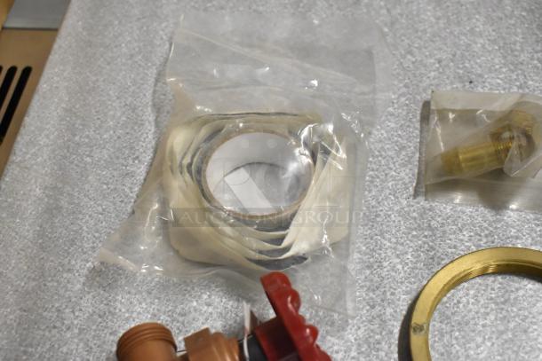 Lot of various items including wrapped coil, brass fitting, red handle, and gold ring on a textured surface.