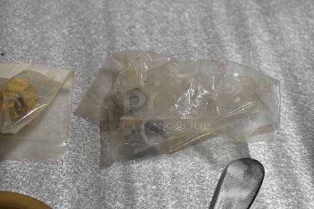 Lot of various items in transparent packaging including metal handles and a rack, shown on a textured surface.