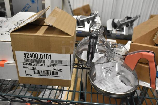Three brand new Bunn coffee pots including model 42400-0101, 12-cup glass decanters with black and orange handles, in original packaging.