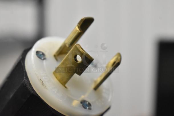 Close-up of a brass electrical plug for a stainless steel commercial espresso machine.