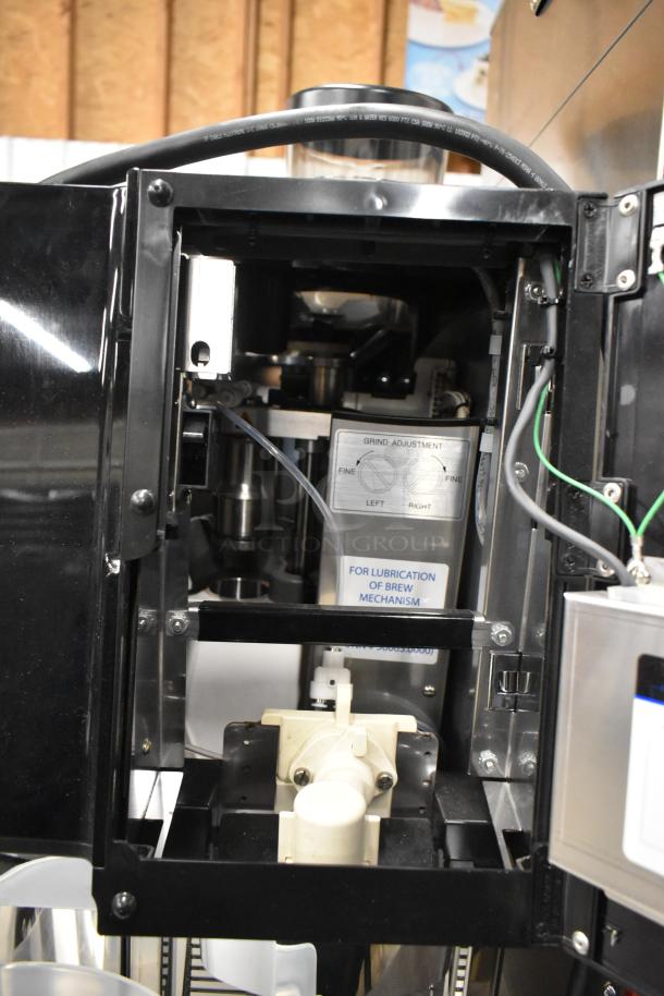 Brand new stainless steel commercial espresso machine with hot water dispenser, 120/208-240V, 1 phase, features grind adjustment and brew mechanism lubrication label.