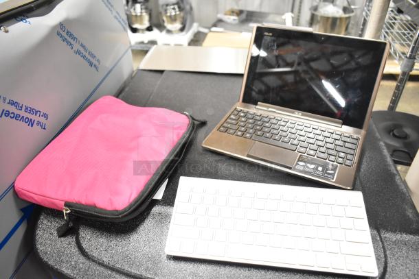 Asus laptop with black keyboard and screen, pink case nearby, and separate white wireless keyboard.
