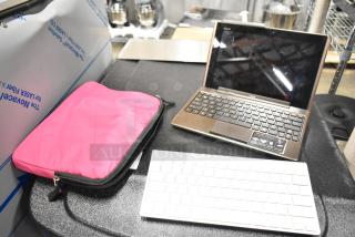 Asus laptop with black keyboard and screen, pink case nearby, and separate white wireless keyboard.