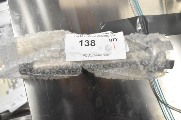 Brand new stainless steel immersion blender blade, wrapped in bubble wrap. Auction tag reads "138." Scratch and dent condition.