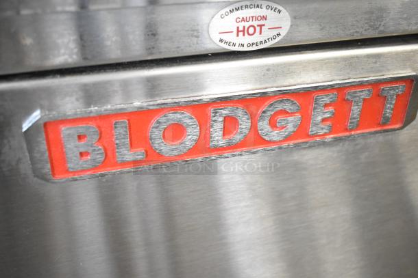 Blodgett stainless steel commercial gas convection oven, solid door, metal racks, thermostatic controls; caution label visible.