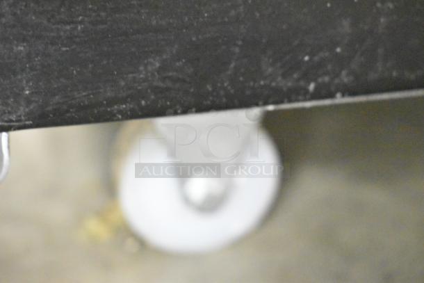 Blurred close-up of a white caster wheel attached to a KoolMore KM-MDR-1GD-10C reach-in cooler.