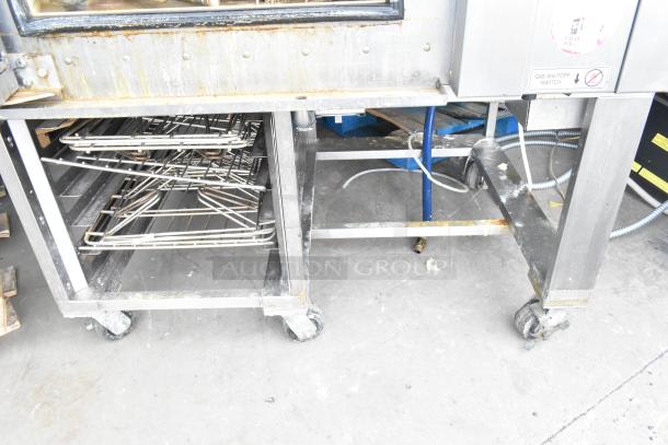 Baxter BV400G stainless steel gas rotating rack oven on casters. Visible wear, signage indicates gas shutoff switch.
