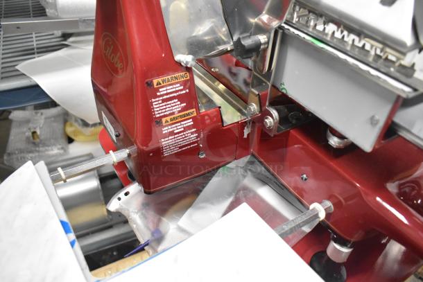 Brand new Globe FS12 metal meat slicer with flywheel, blade sharpener, warning labels, and visible Globe logo.