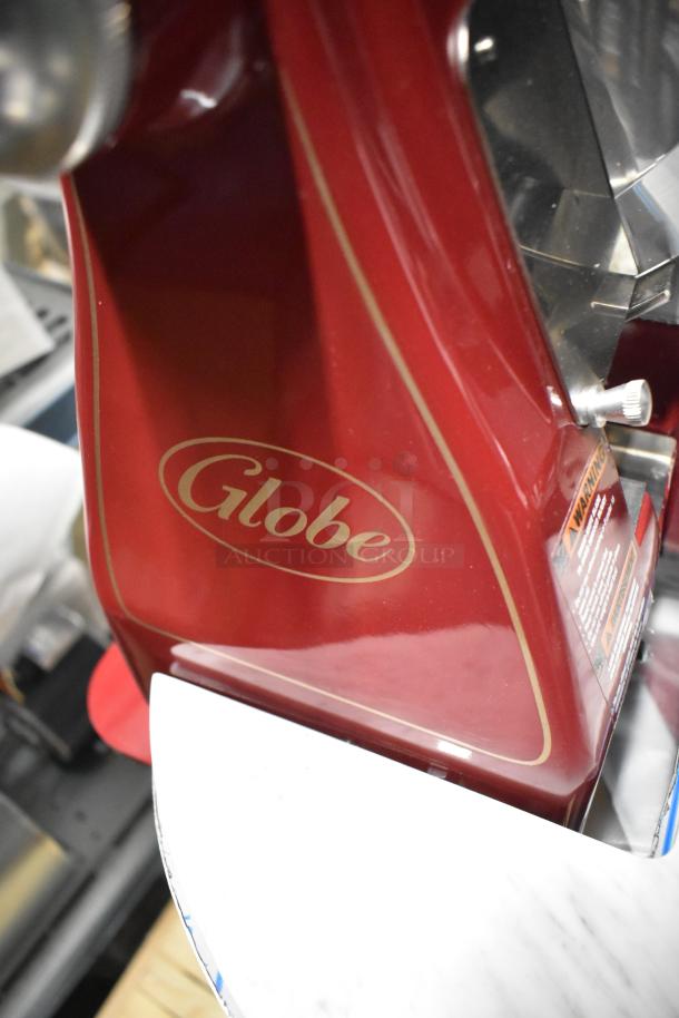 Brand new Globe FS12 manual meat slicer, red metal, with blade sharpener, warning label, polished finish.