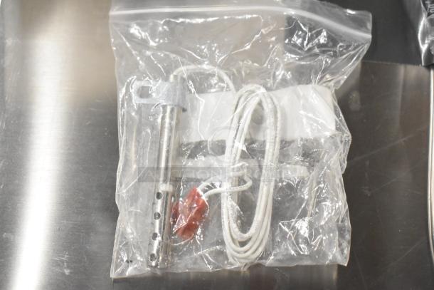Clear plastic bag containing new coil and thermostatic control with white cord. Auction includes five brand new items.