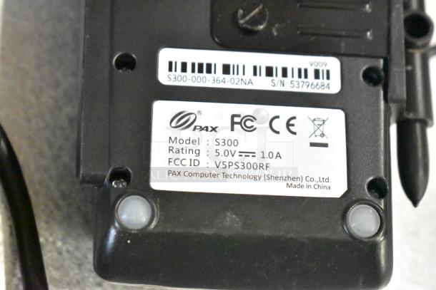 PAX S300 model label on a device, indicating 5.0V, 1.0A, FCC ID V5PS300RF, made by PAX Computer Technology.