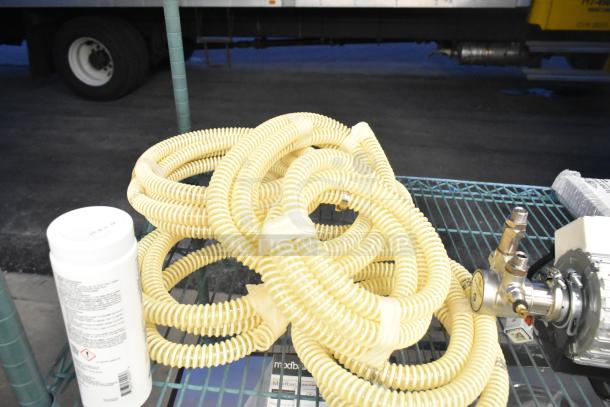 Coiled yellow hoses from La Marzocco Modbar Espresso AV System, new condition, next to metal valves and container.