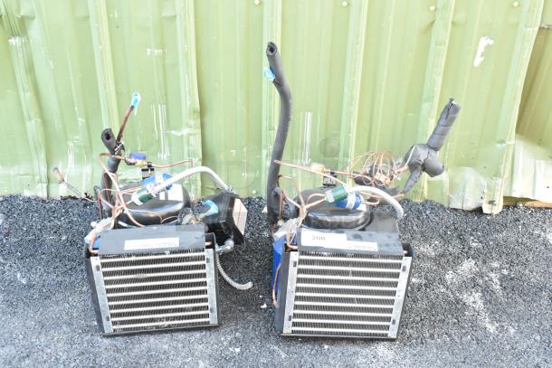 Two brand new Copeland M7JP-H021-IAA-072 compressors. 115 volts, 1 phase. Includes cooling coils, labels visible.
