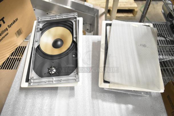 Two Control 126WT in-wall loudspeakers, featuring a beige woofer. Comes with protective grilles. Ideal for high-quality audio.