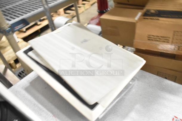 2 JBL Control 126WT in-wall loudspeakers, white, used condition. Grills slightly ajar, stored near cardboard boxes.